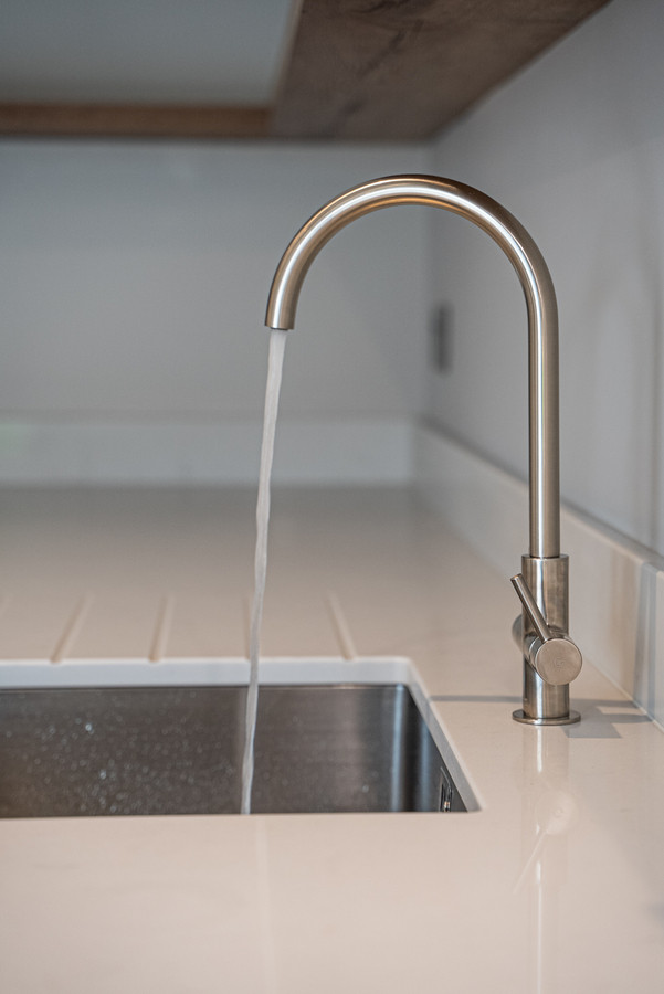 Modern kitchen tap with running water.