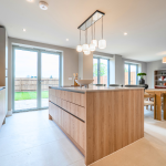 Modern kitchen and dining area with warm tones and textures throughout at Avon Bard, a collection of bespoke homes in Stratford Upon Avon.