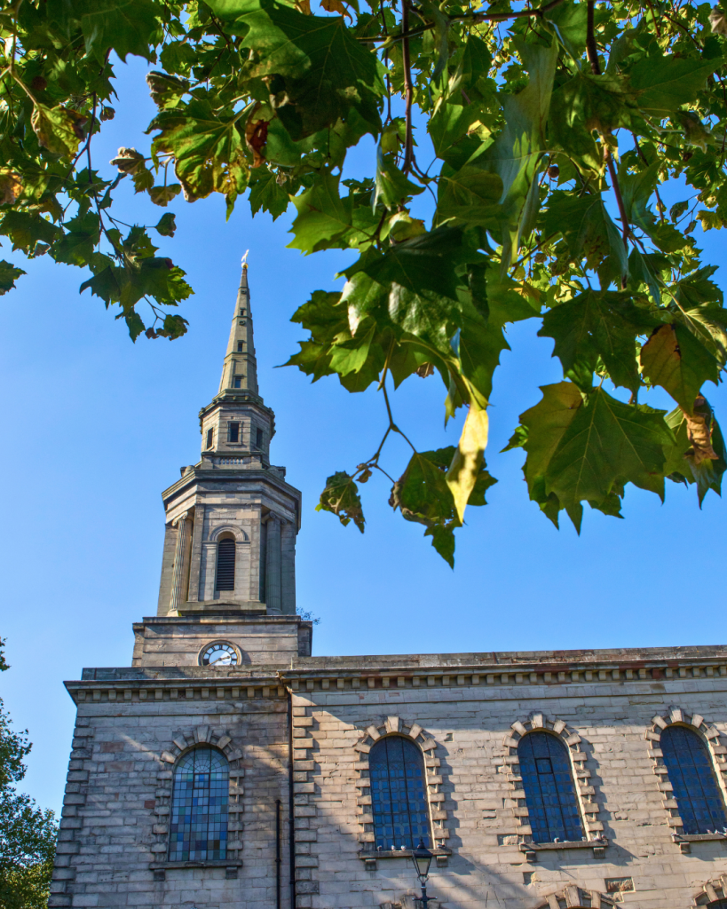 St Pauls Church spire framed by green leaves in St Pauls Square - Jewellery Quarter, Birmingham.