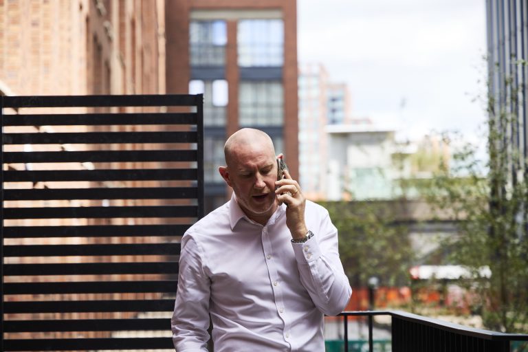 Man speaking on phone outdoors.